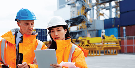 British Safety Council Consultancy Services - Man and woman on work site in hard hats and high visibility jackets looking at an i-pad