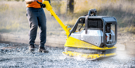 Person using heavy vibrating machinery to pack down tarmac