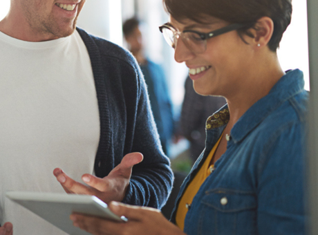 Man and woman stood in office having a conversation over a tablet