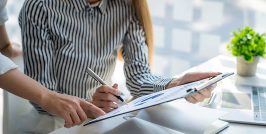 lady holding a document with a pen and graphs