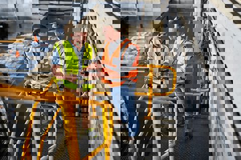 Two men stood in warehouse discussing information on a clipboard