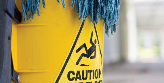 Blue mop in a yellow bucket labelled &quot;Caution wet floor&quot;
