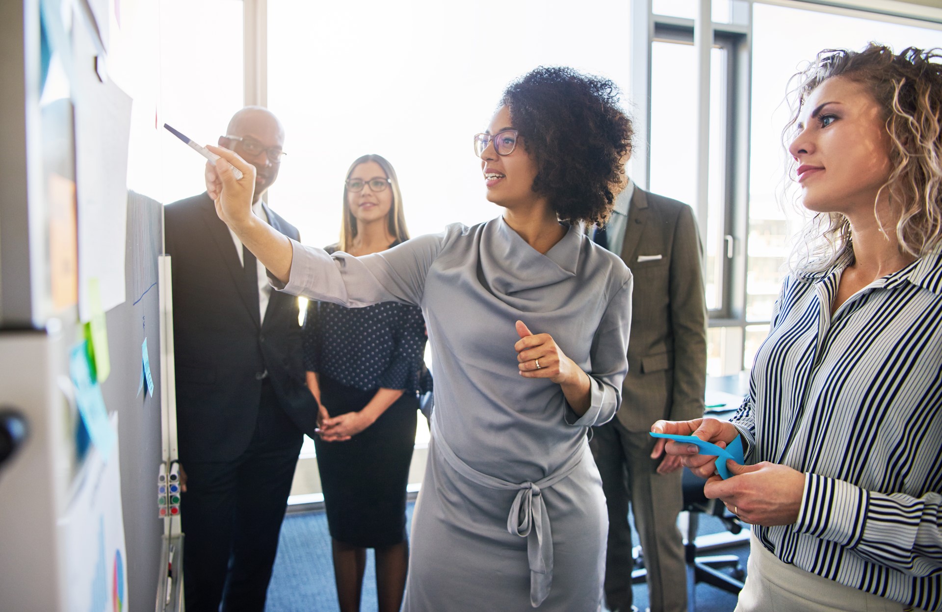 A group of people in an office working together and making notes on a whiteboard