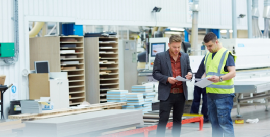 Two men stood in a warehouse reviewing documents