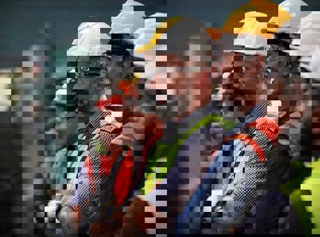 A row of men stood next to each other wearing high vis jackets and PPE