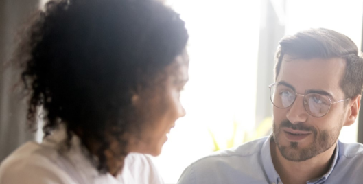 Man and woman having a conversation in front of a brightly lit window