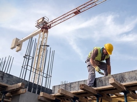 Man wearing PPE working on construction site with a crane in the background