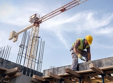 Man wearing PPE working on construction site with a crane in the background