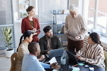 Diverse group of people having a discussion around a table in a meeting room in an office