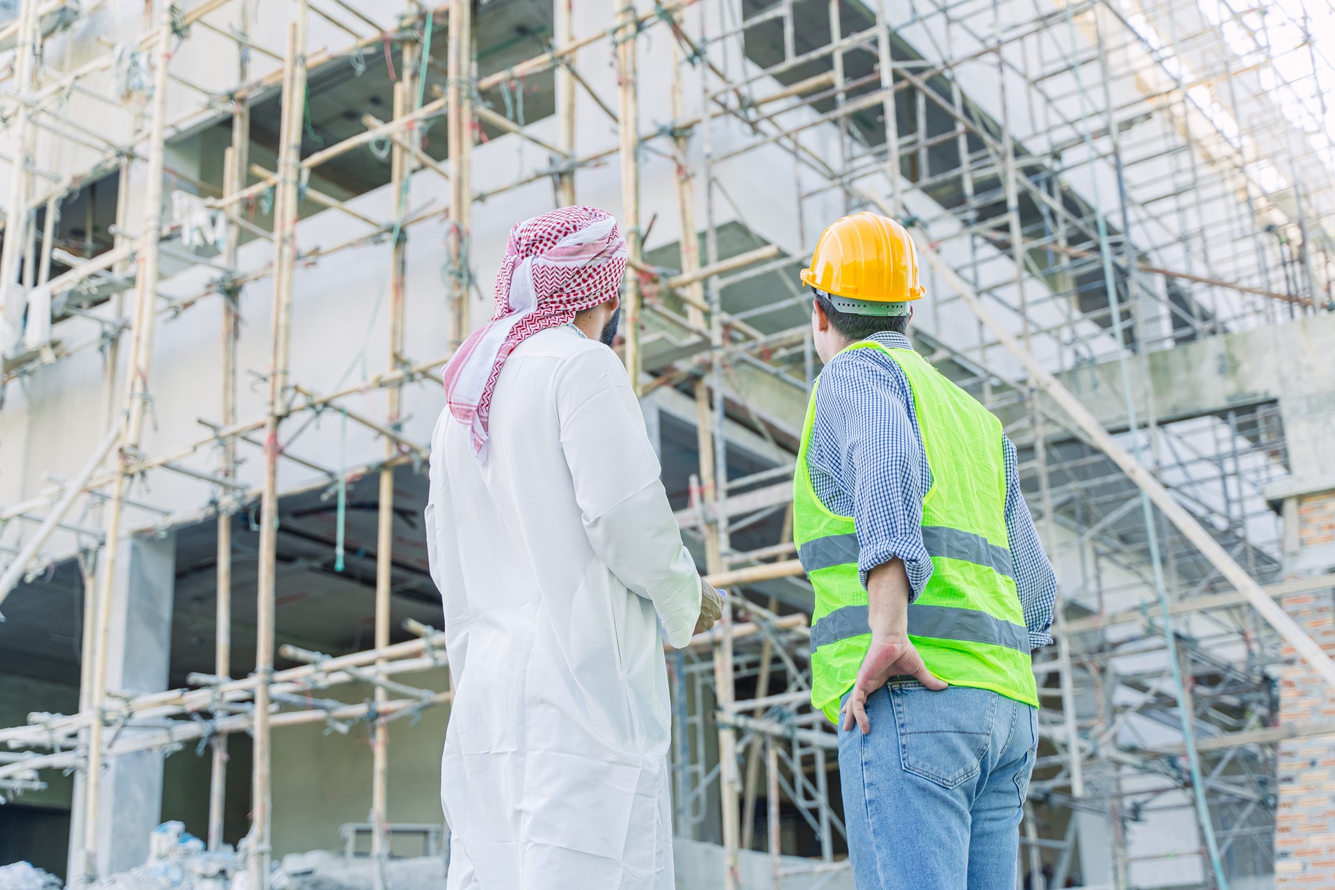 A man and a safety worker looking up at a construction site
