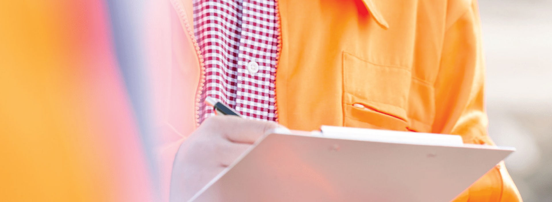 Man in orange hi vis writing on clipboard