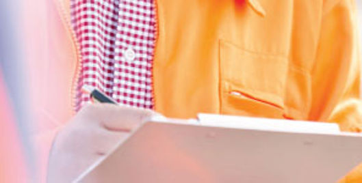 Man in orange jacket writing on a clipboard