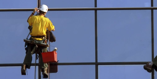 Two window cleaners working at height wearing PPE
