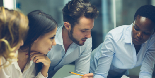 Close up of four people huddled around a desk