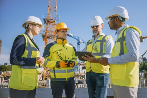 Four people wearing PPE having a conversation at a construction site